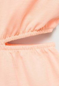 Breskve barve, raztegljiv zgoraj iz tkanine z nabranim elastičnim detajlom in izrezom. Mehak material, primeren za vsakodnevno nošnjo.