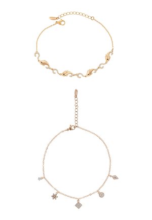 Dwie delikatne bransoletki z złotych łańcuszków, jedna z akcentami delfina i kryształów, druga z pięcioma małymi geometrycznymi i gwiazdkowymi zawieszkami.