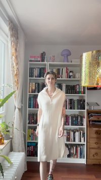Robe blanche à côtes, à mi-mollet, avec col polo et manches courtes. Présente une texture subtile, portée avec des baskets à motifs.