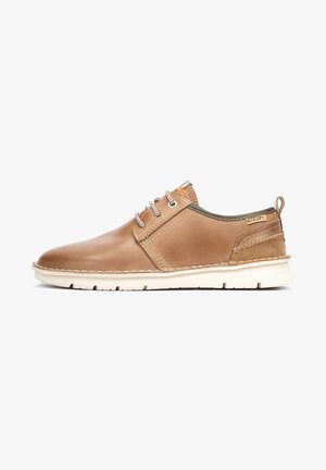 Zapato de piel marrón con punta redondeada, suela blanca contrastante, cordones bicolores y un pequeño logo en el talón. Presenta un acabado texturizado.