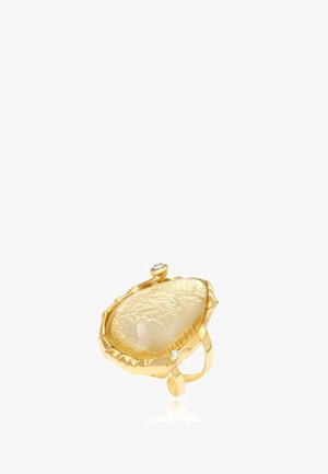 Bague en or avec une grande pierre précieuse jaune translucide texturée et deux petits pierres d'accent claires sur la monture.