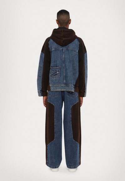 Denim jacket with brown accents, oversized hood, and large patch pockets, paired with wide-leg denim pants featuring brown side panels.