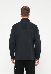 Zwarte langemouwenshirt met een kraag, knoopmanchetten en een rechte snit. Gemaakt van een soepele stof, met een rugboord detail.