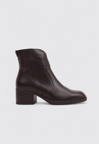 Botín de cuero marrón hasta el tobillo con tacón cuadrado, que presenta un diseño elegante, textura suave, cremallera lateral y un estilo minimalista.