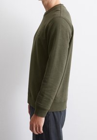 Bluza oliwkowa z miękkiego materiału, z okrągłym dekoltem, ściągaczami na mankietach i subtelną fakturą. Prosty design bez widocznych logo.