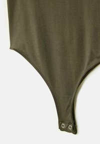 Onderkant van een olijfgroene stoffen body met drukknoopsluiting in het kruis, getoond op een lichte achtergrond.