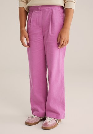Roze corduroy broek met wijde pijpen, geplooide voorkant en een enkele knoopsluiting. Gepaard met lichtroze sneakers en witte veters.