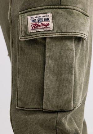 Olivegrüne Cargo-Hose aus einem strukturierten Stoff, mit einem auffälligen Patch-Label "BIG STAR LIMITED" und einer großen Seitentasche.