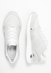 Šedé tenisky s kombinací texturované tkaniny a semiše, s perforovanými akcenty, bílými tkaničkami a gumovou podrážkou.