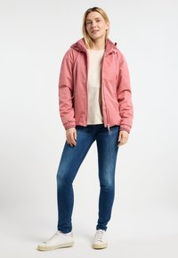 Ljust rosa, huva jacka med dragkedja fram, insnörda ärmslut och sidofickor. Kombinerad med blå jeans och vita sneakers.
