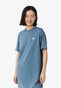Vestito in cotone blu a maniche corte, con una vestibilità comoda e collo tondo. Presenta un piccolo logo bianco sulla parte sinistra del petto.