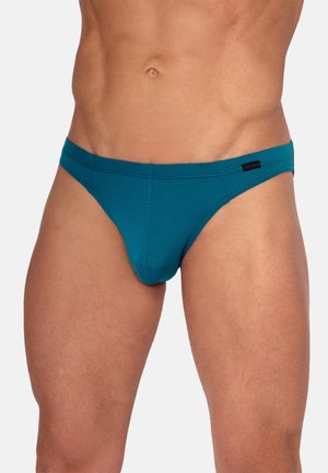 Slanke mannelijk torso met groene geribbelde slips en een klein zwart merkembleem aan de rechterkant van de tailleband.