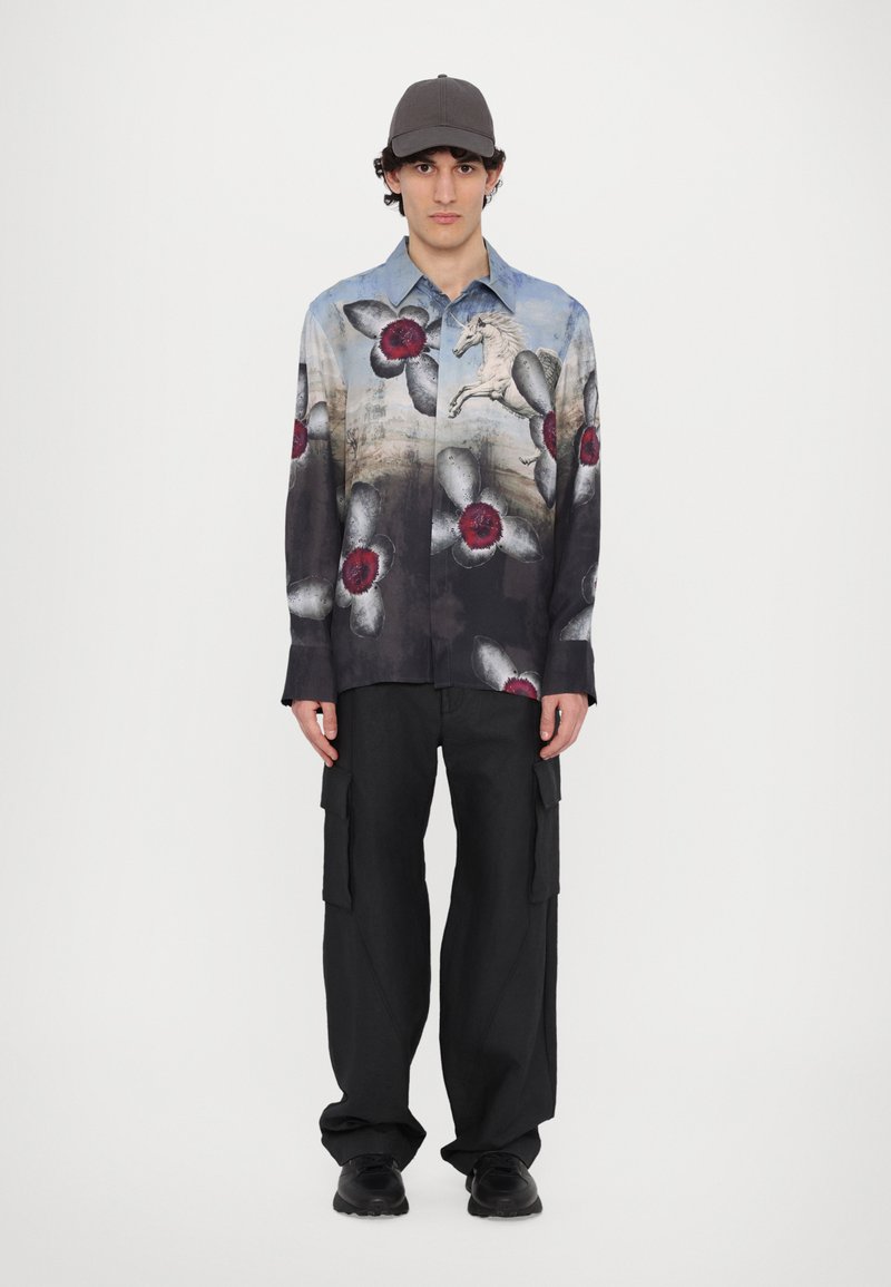 Floral-patterned long-sleeve shirt in shades of blue and black, featuring red and grey flowers, paired with black cargo pants and a grey cap.