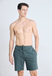 Kaki grønne shorts laget av teksturert stoff med justerbar snøring i livet og sidelommer. Har en subtil logo-detalj.