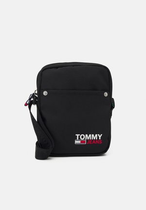 Schwarze Stoffschultertasche mit Reißverschluss, ausgestattet mit einer Fronttasche und dem "TOMMY JEANS"-Logo in Weiß und Rot. Verstellbarer Tragegurt inklusive.