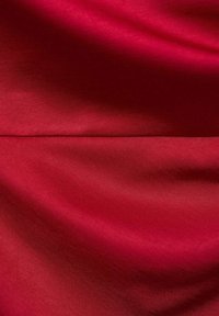 Red fabric with a smooth, shiny texture, featuring a rich depth of color and subtle light reflections across the surface.