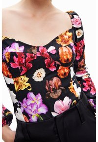 Schwarze Bluse mit floralem Muster, die lebendige pinke, orangefarbene und weiße Blumen zeigt, mit einem quadratischen Ausschnitt und Puffärmeln, aus leichtem Material gefertigt.