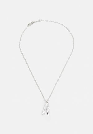 Colier din argint cu un pandantiv texturat, având două piese alungite, una cu puncte negre mici, suspendate de o lanț delicat.