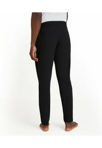Zwarte stretchstof broek met een geplooide elastische tailleband, slim fit en een gladde textuur. Beschikt over zijzakken en taps toelopende benen.