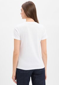 Witte katoen t-shirt met een ronde hals en korte mouwen, met een gladde textuur en een klassieke pasvorm, gedragen met donkere spijkerbroek.