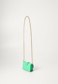 Mână de mână rectangulară mică, verde strălucitor, cu închidere tip clapă și curea subțire din aur, atârnând pe un fundal alb.
