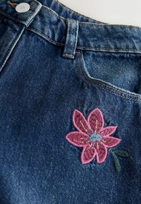 Falda de mezclilla con un lavado azul oscuro; presenta una flor bordada en rosa con hojas verdes; incluye un bolsillo delantero y botón de metal.