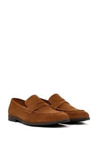 Mocasines de ante marrón con un diseño de estilo mocasín, detalles cosidos y una suela de goma de perfil bajo. Estética minimalista, sin herrajes.