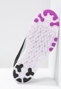 Schwarze Sport Schuhsohle mit einem sechseckigen Muster in Weiß und lila Akzenten. Glatte Textur mit deutlich erkennbarer Traktionsgestaltung für besseren Halt.