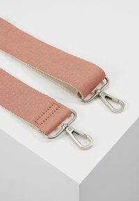 Tracolla in tessuto regolabile di colore rosa polveroso, con clip in metallo argentato ad ogni estremità, finitura testurizzata e dettagli di cuciture visibili.