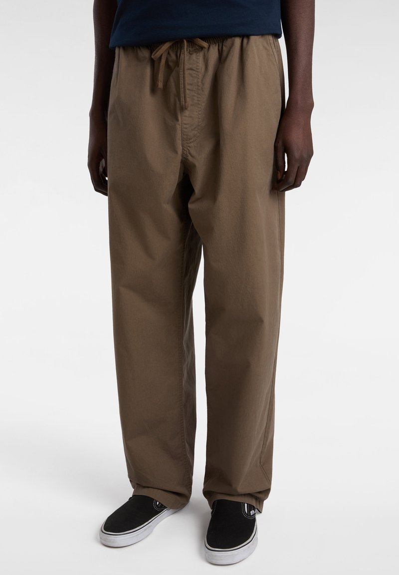 Brown cotton pants with an elastic waistband and drawstring, featuring a relaxed fit and straight legs, paired with black slip-on shoes.