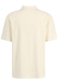 Camisa de polo de manga corta en color crema claro. Fabricada con un tejido suave, presenta un cuello clásico y un dobladillo limpio sin patrones visibles.