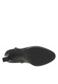 Chaussure noire à talons avec une semelle en caoutchouc texturée et un design supérieur élégant. Talon carré et finition lisse, mettant en avant un detailing minimaliste.