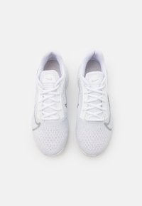 White athletic shoes with a mesh upper, lace closure, padded collar, and a gray logo accent on the side. Textured sole for grip.
