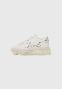 Zapatilla blanca con suela transparente, acentos plateados y "Karl" bordado en el lateral. Punta redondeada y diseño con cordones.