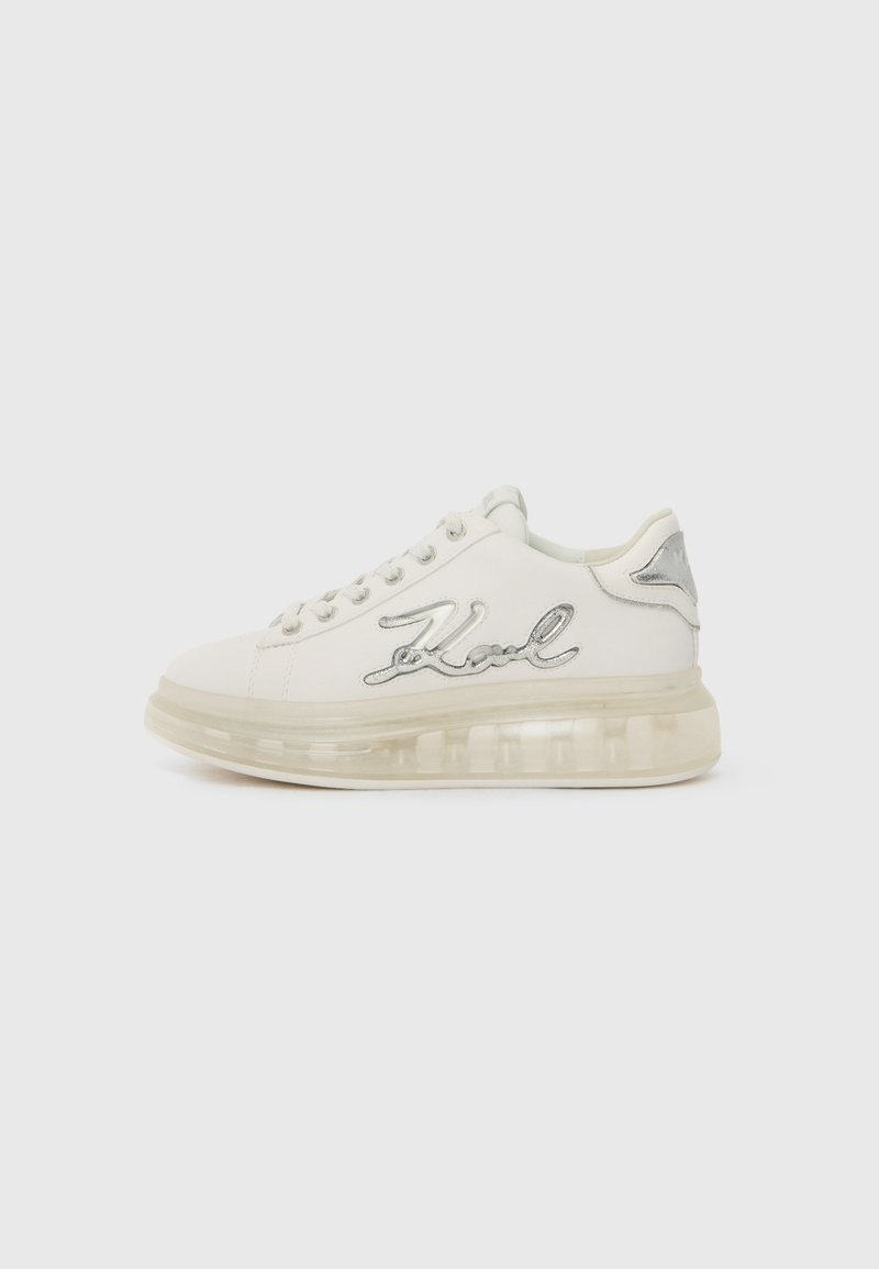 Zapatilla blanca con suela transparente, acentos plateados y "Karl" bordado en el lateral. Punta redondeada y diseño con cordones.