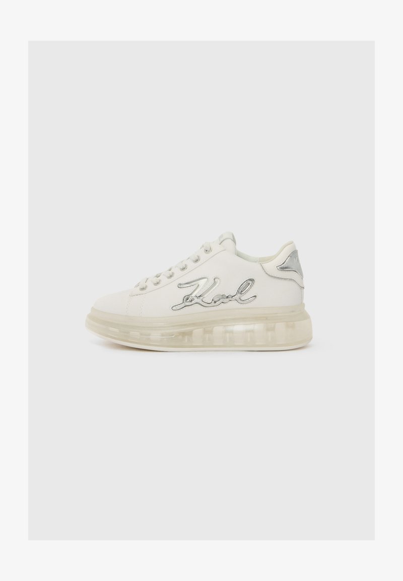 White sneaker with a transparent sole, silver accents, and "Karl" embroidered on the side. Rounded toe and lace-up design.