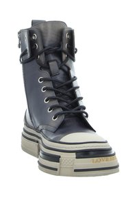 Black leather high-top boot with lace-up front, silver hardware, and cream-colored toe cap. Features a thick, patterned platform sole.