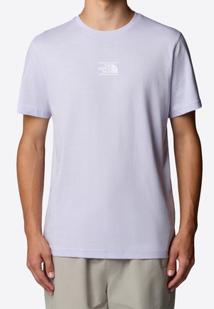 Mand iført en ensfarvet lys lilla T-shirt med korte ærmer og lille hvid The North Face-logo centralt på brystet.