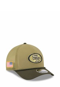 Olivengrüner Baseballcap mit strukturierter Form, Logo-Patch in Gelb und Schwarz auf der Vorderseite sowie einem kleinen amerikanischen Flaggenakzent an der Seite.