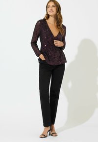 Langarmige paarse sequinkraag met een diepe V-hals en een geraffineerde taille, gecombineerd met zwarte rechttoe rechtaan broek en zwarte hakken met bandjes.