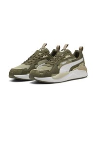 Olivgröna sneakers med mesh- och mockatexturer, vita accenter, vadderad tunga och snörning. Har signaturlogotyp på sidorna.