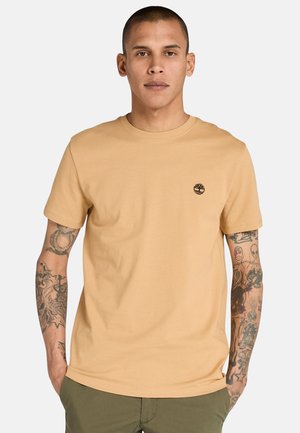 T-shirt in cotone beige con collo rotondo e maniche corte. Presenta un piccolo logo nero sul petto. Texture liscia, design semplice.