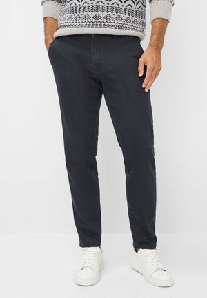Chino grigio scuro realizzati in tessuto di cotone misto, con un design a gamba dritta, una texture sottile e tasche frontali. Abbinati a sneakers bianche.