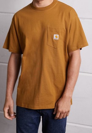 Kortærmet, sennepsfarvet bomulds t-shirt med en brystlomme og et firkantet Carhartt-mærke. Glat tekstur, afslappet pasform.