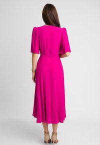 Fuksjowa sukienka z krótkimi bufiastymi rękawami, wcięciem w talii, spódnicą w lekkim ruchu i długości do kolan. Gładka tkanina elegancko się układa.