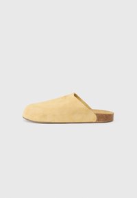 Yellow suede slip-on shoe with a rounded toe, minimal design, and a textured finish. Features a cork sole for comfort.