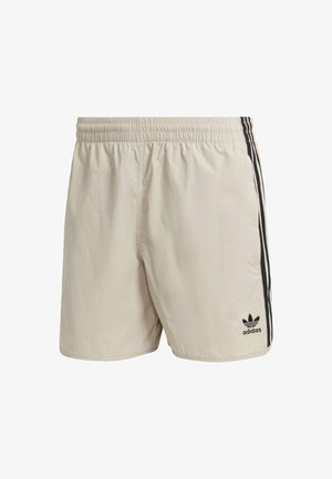 Shorts beige clair avec une taille élastique, des rayures noires sur les côtés et un logo Adidas en bas à gauche à l'avant. Fabriqués dans un matériau lisse et léger.