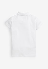 Chemise polo blanche à manches courtes, col plat et texture en coton doux. Design simple sans motifs ni accents supplémentaires.