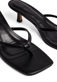 Mustad nahast kontsaga sandaalid nelinurkse varbaga, õhukeste rihmadega ja väikese plokknööriga. Sile tekstuur koos õmblustega.