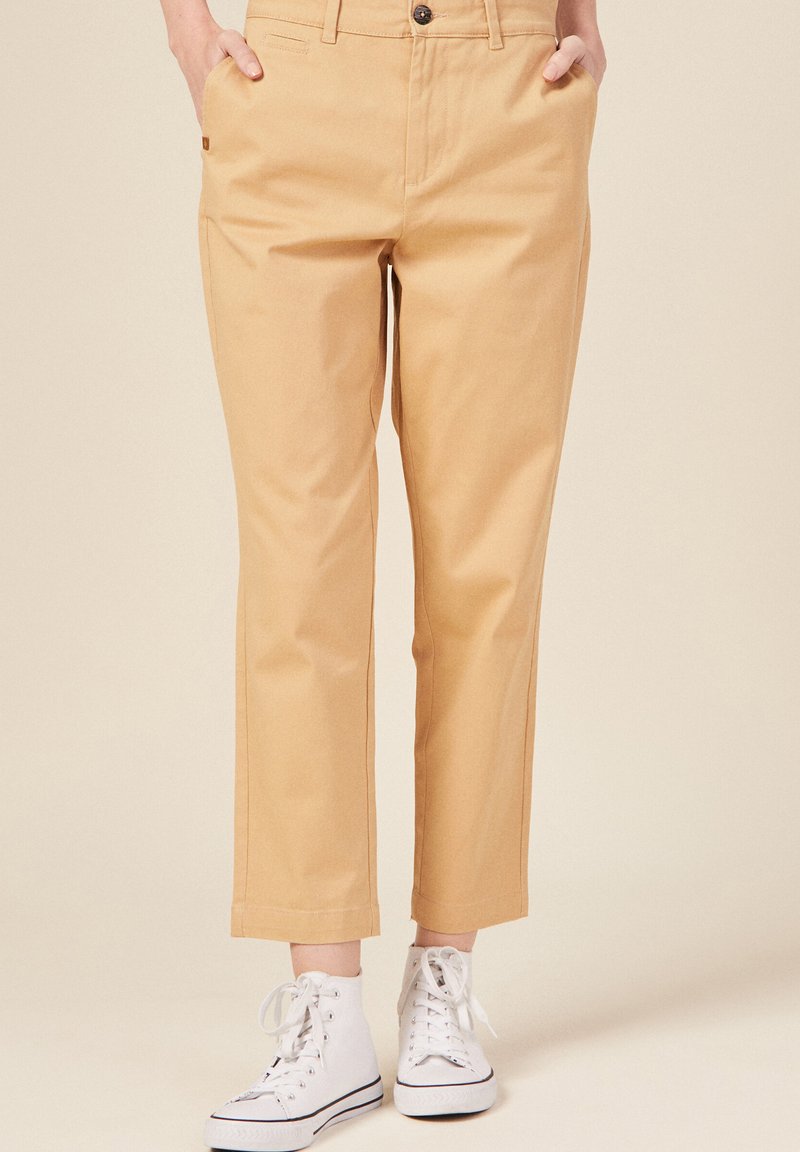 Kaki cropped broek gemaakt van katoen, met zijzakken, een knoopsluiting en een recht model. Gecombineerd met witte hoge sneakers.
